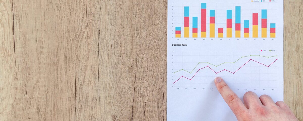 person pointing paper line graph